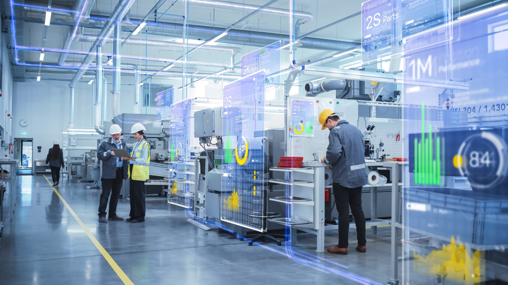 A modern industrial facility with high ceilings, bright lighting, and advanced machinery. Several workers in safety gear, including hard hats and high-visibility vests, are engaged in monitoring and discussing operations. Augmented reality (AR) overlays display real-time data, including performance metrics, graphs, and required parts, suggesting the use of IoT and digital asset monitoring solutions in a smart factory environment.